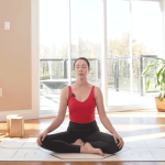 woman sitting on a yoga mat with her legs crossed and hands on thighs