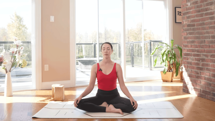 woman sitting on a yoga mat with her legs crossed and hands on thighs