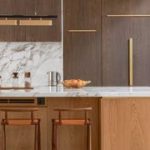 timber kitchen with marble counters, a pot plant, jars, kettle, and fruit bowl