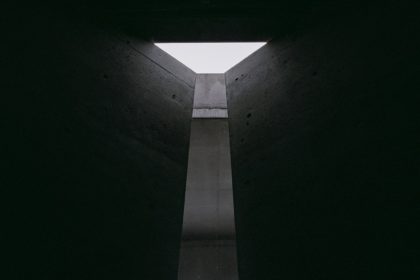 still from The Brutalist with light pouring into dark room through triangular skylight into shaft below