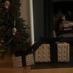 Two stud embellished christmas presents by a fireplace and a small Christmas tree