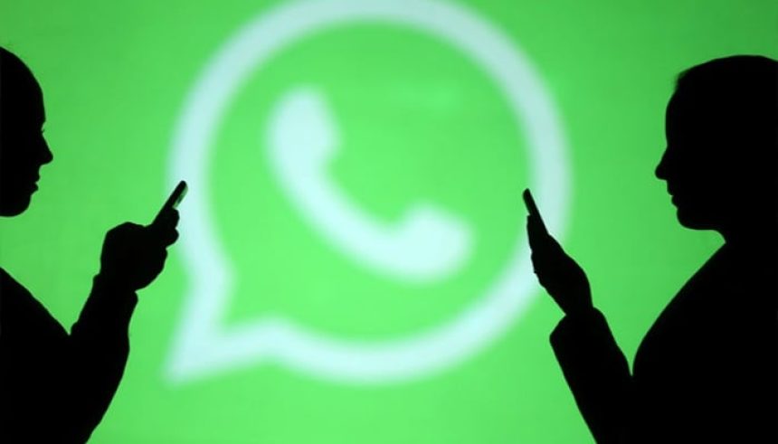 Silhouettes of mobile users are seen next to a screen projection of Whatsapp logo in this picture illustration. — Reuters