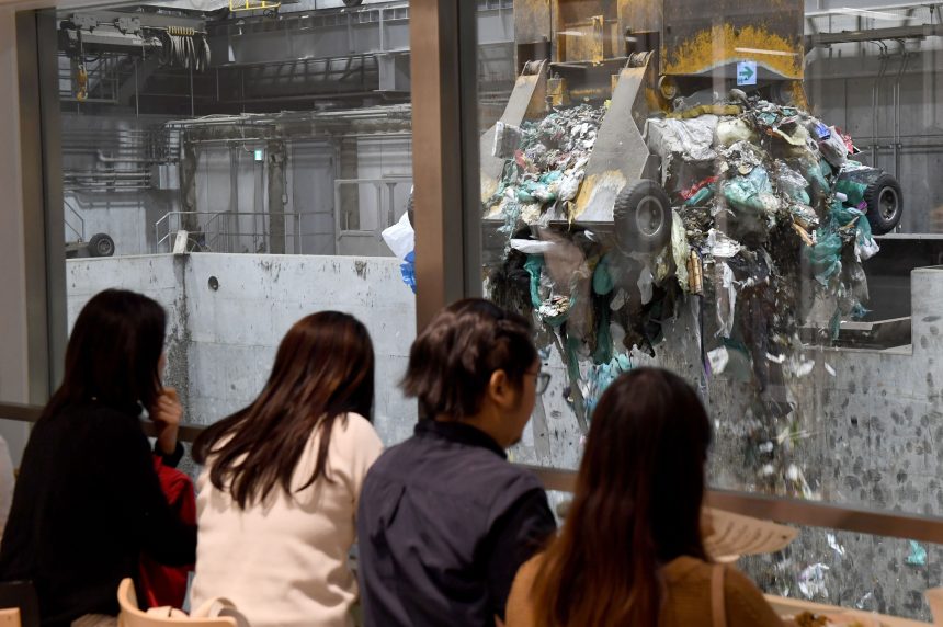 Customers watch a crane pick up rubbish for incineration at a combustible waste pit at the ‘Gomi Pit’ bar in Tokyo