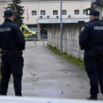 Two Croatian police officers stand guard outside of a school.