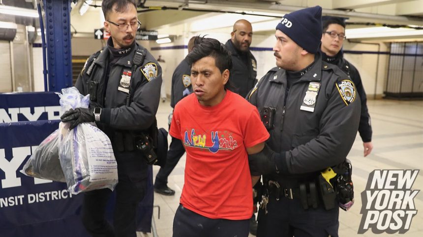 NYPD officers escort a suspect wanted for a homicide on the F Train in Coney Island