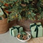 A close-up of the bottom of the Christmas tree with green wrapped gifts and a bowl of baubles