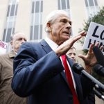 Peter Navarro talking to media on the sidewalk as activists surround him