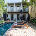 Swimming pool and tiled deck with house in the background.