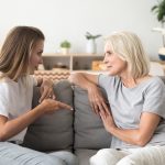 Two women sat on a sofa having a serious conversation