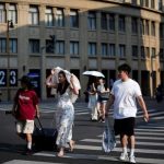 People cross a street amid an alert for heatwave in Shanghai, China August 10, 2023. — Reuters