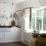 A utility room with white cabinetry , open shelving, and a laundry maid drying rack hanging from the ceiling