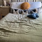 Made up bed featuring a green linen quilt