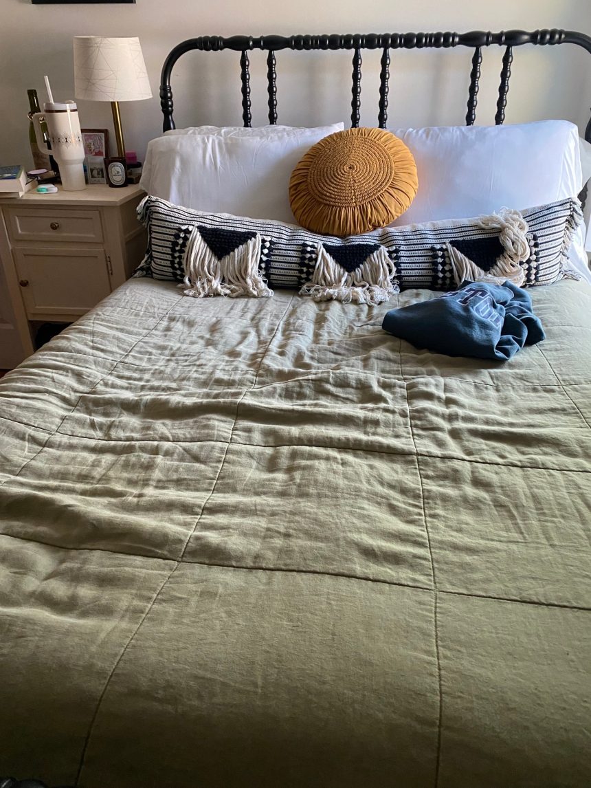 Made up bed featuring a green linen quilt