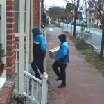 The two men disguised as Amazon workers approaching Hardison's door