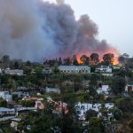 LA fire with smoke filling sky homes on fire in treelined neighborhood