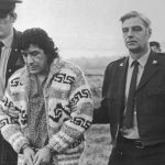 Leonard Peltier, American Indian Movement leader, is led across Okalla prison exercise yard to a waiting helicopter. After a prolonged legal battle, Peltier was ordered deported by Canadian Justice Minister Ron Basford to face charges of murdering two FBI agents.