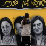 A girl pauses at a mural of female Israeli soldiers