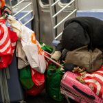 homeless man with their belongings in subway