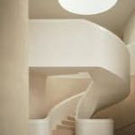 A monumental staircase crafted from microcement and European oak winds from the basement to the third level of a 12,000-square-foot house in rural Oxfordshire, England.