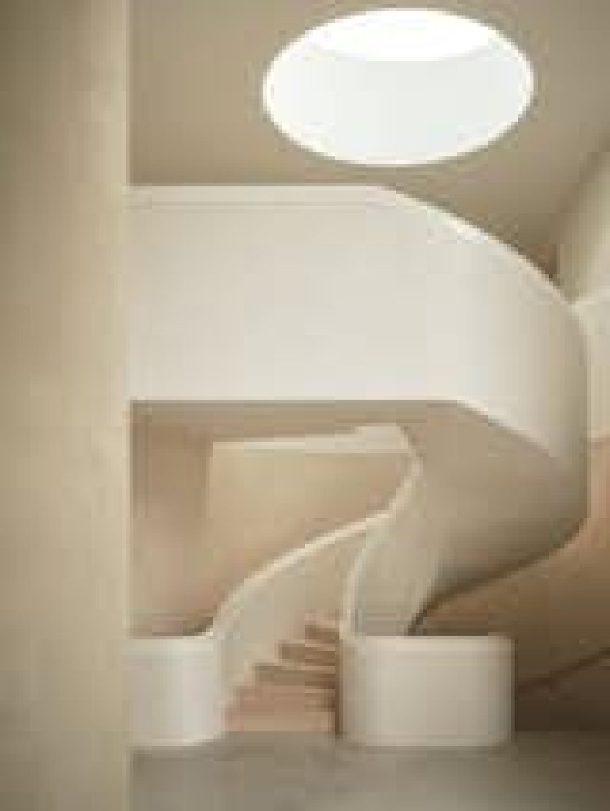 A monumental staircase crafted from microcement and European oak winds from the basement to the third level of a 12,000-square-foot house in rural Oxfordshire, England.