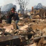 Two people embrace as they inspect a family member's property that was destroyed by Eaton Fire