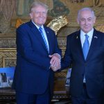 Former US President Donald Trump shakes hands with Israeli Prime Minister Benjamin Netanyahu as they pose for a photo within their meeting at Mar-a-Lago estate