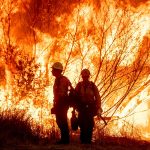 firefighters silhouetted by flames