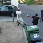 a man holding what appears to be a fuel tank and blowtorch nozzle as a homeowner confronts him