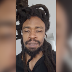 Mel Horne with dreadlocks and beard wearing a black shirt