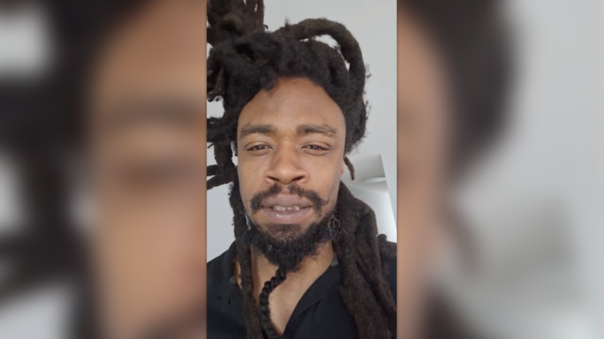 Mel Horne with dreadlocks and beard wearing a black shirt