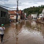 man wades through helene waters in NC