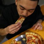 Chef Quin Jianoran has a taste of the Hawaiian, ham, and pineapple-topped pizza at Lupa Pizza restaurant in Norwich