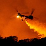 helicopter drops water on the Palisades Fire