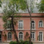 Exterior of Casona Roma Norte painted pink with arched windows.