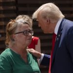 Patty Morin in green and Donald Trump in a navy blue suit speak at the border wall in Arizona