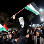 A man waves a Palestinian flag in Deir el-Balah in the central Gaza Strip. [Ramadan Abed/Reuters]