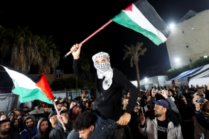 A man waves a Palestinian flag in Deir el-Balah in the central Gaza Strip. [Ramadan Abed/Reuters]