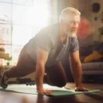 Strong Athletic Fit Middle Aged Man Doing Mountain Climber Exercises During Morning Workout at Home in Sunny Apartment. Healthy Lifestyle, Fitness, Recreation, Wellbeing and Retirement.