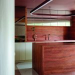 An Earthy-textured kitchen island with metallic overhead cupboards