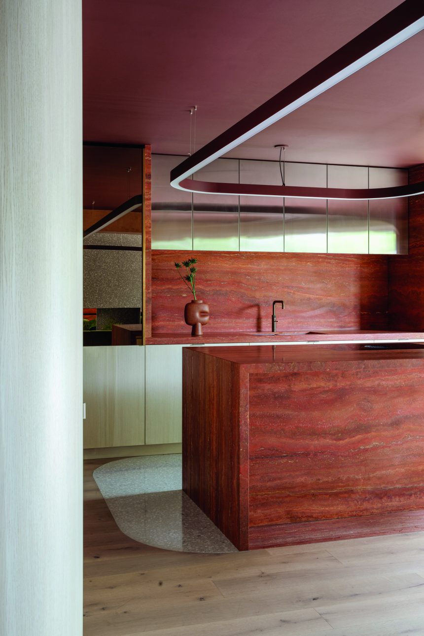 An Earthy-textured kitchen island with metallic overhead cupboards