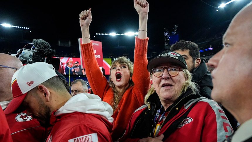 Taylor Swift puts her arms up wearing a red sweater and cheers for the Chiefs alongside Donna Kelce in Chiefs gear after Kansas City wins the AFC Championship