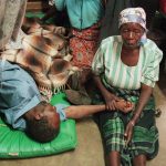 A woman holds the hand of a sick relative lying on the floor of the overcrowded Lilongwe Central Hospital, in Lilongwe, Malawi, 1998 (file photo)