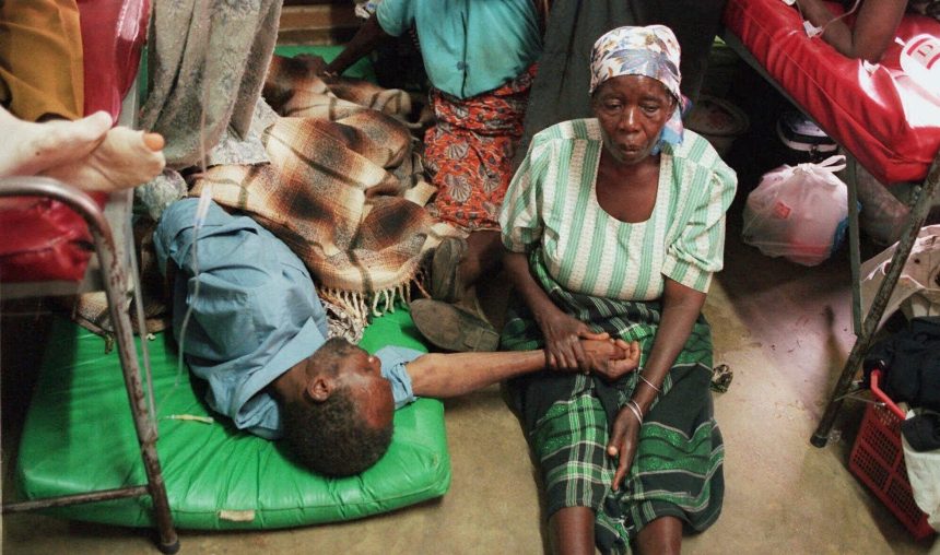 A woman holds the hand of a sick relative lying on the floor of the overcrowded Lilongwe Central Hospital, in Lilongwe, Malawi, 1998 (file photo)