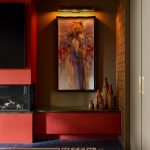 A living room with a blue carpet and an earthy rug, surrounded by red cabinets