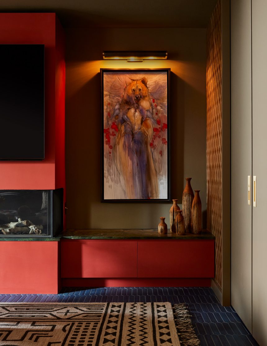 A living room with a blue carpet and an earthy rug, surrounded by red cabinets