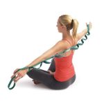 Image of woman sitting down and gripping a green Stretch Out Strap behind her back with both arms extended.