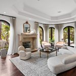 living area of Kris Kardashians home white ceiling dark wood flooring arched glass doors line rounded space curved sofa...