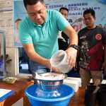 Village chief Carlito Cernal (C) pours a plastic container filled with water and mosquito larvaes handed over by residents into a strainer for counting at the start of peso for a mosquito programme to eradicate dengue in Manila on February 19, 2025. — AFP