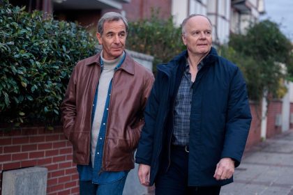 Two middle-aged men walking down pavement on residential road