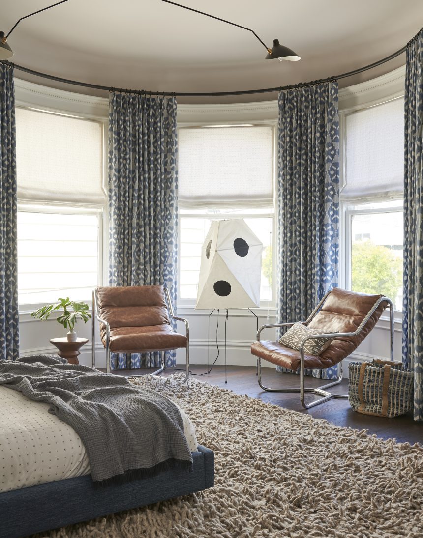 bedroom with lots of natural light, two brown leather armchairs, curtains over sheers and a shag rug